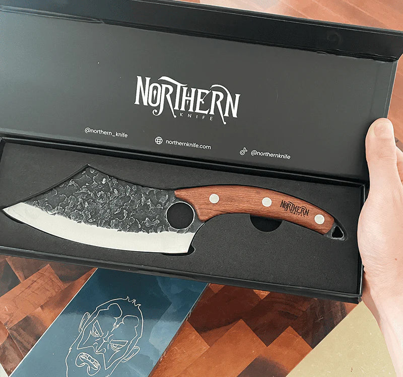 The Viking-style butcher knife with a finger hole, showcased inside a premium Northern packaging box and held by a customer.