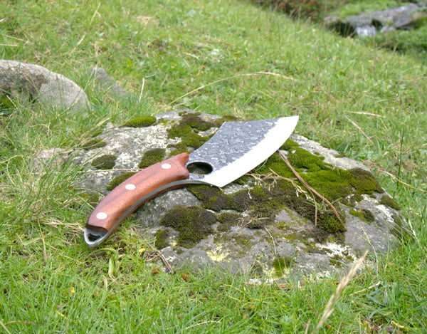 The Loki knife placed on a mossy stone in nature, showing its durability and outdoor-ready build as praised in the customer review.
